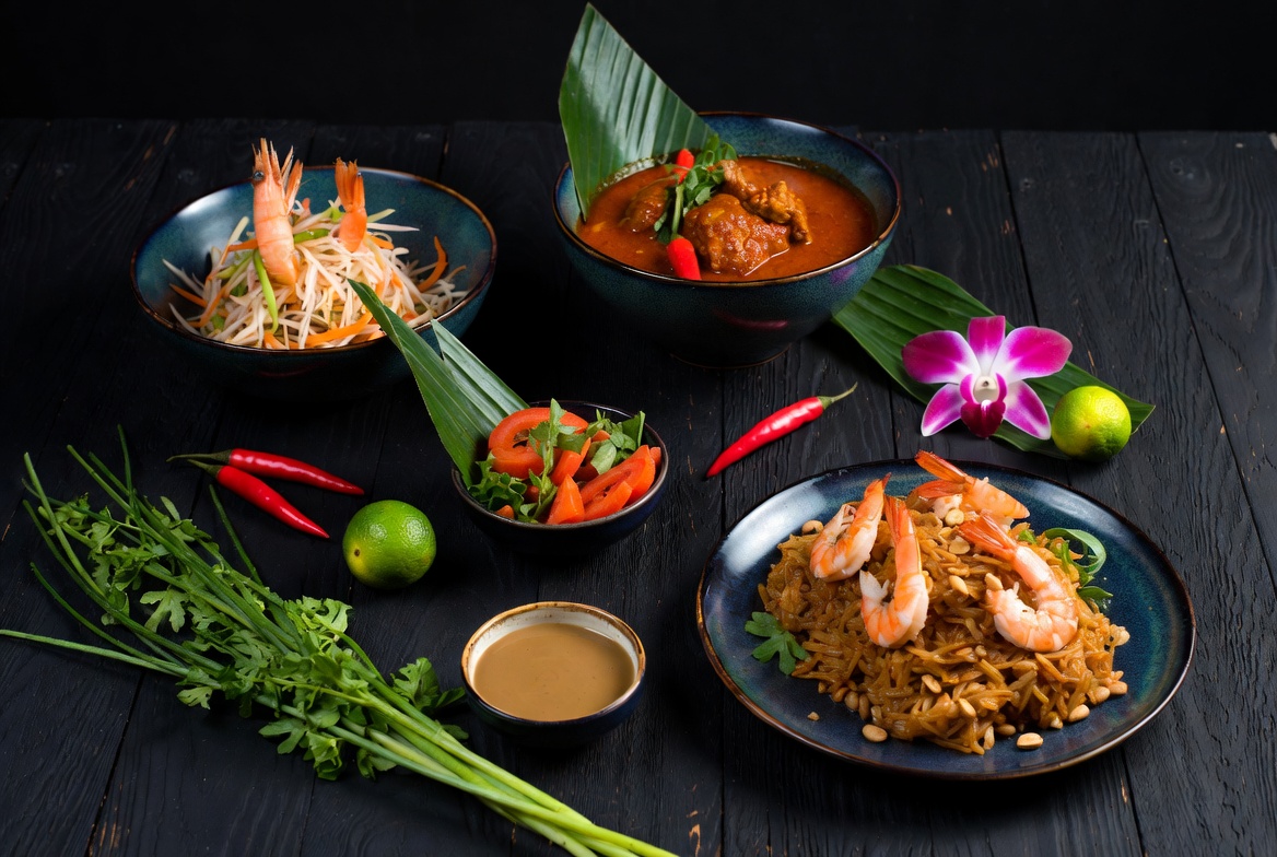 Thailändisches Festmahl mit Curry, Pad Thai und frischen Kräutern